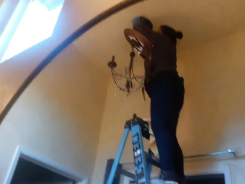 Electrician installing a chandelier in a Bogota residence